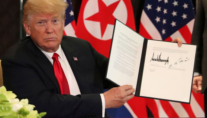 Президент США Дональд Трамп с подписанным документом после встречи с высшим руководителем КНДР Ким...