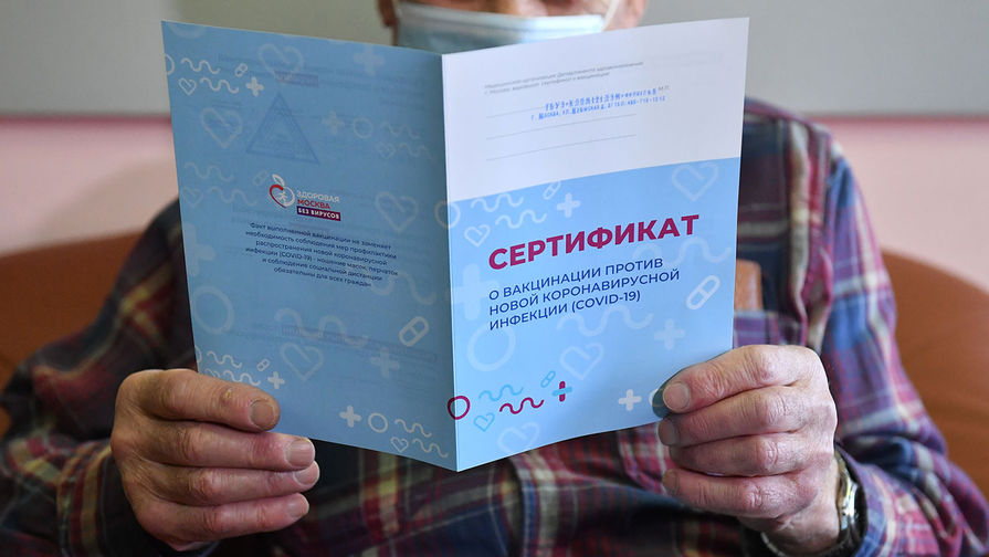  Мужчина держит в руках сертификат о вакцинации против коронавирусной инфекции (COVID-19) 