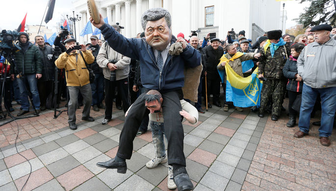 Участник протестного митинга перед зданием Верховной рады в центре Киева в маске президента Украины...