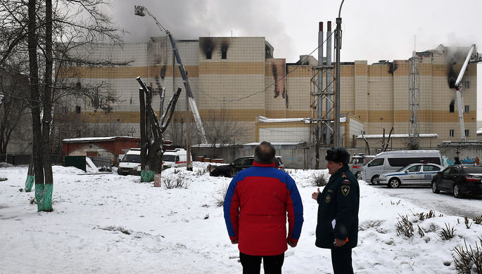 Глава МЧС РФ Владимир Пучков (слева) у горящего торгово-развлекательного центра «Зимняя...