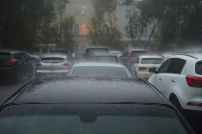 Автомобили под дождем, припаркованные во дворе жилого дома в Москве