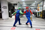 Люди в костюмах Super Mario танцуют во время начала продаж игровой консоли Nintendo Switch 2 в Париже