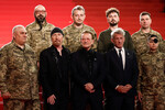 Музыканты Боно, Эдж и актер Шон Пенн с украинскими военнослужащими на красной дорожке Каннского фестиваля перед премьерой документального фильма «Боно: истории капитуляции», 16 мая 2025 года