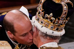 Принц Уильям целует отца короля Великобритании Карла III во время церемонии коронации в Вестминстерском аббатстве, Лондон, 6 мая 2023 года

