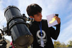 Мальчик наблюдает за солнечным затмением с помощью телескопа в Масатлане, Мексика, 8 апреля 2024 года
