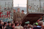 Восточногерманские пограничники стоят в проеме снесенной Берлинской стены возле Потсдамской площади, 11 ноября 1989 года