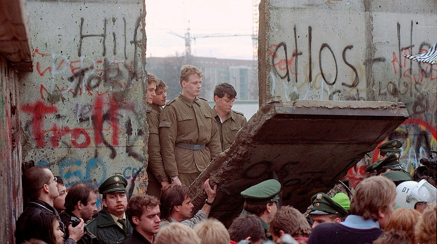 Восточногерманские пограничники стоят в&nbsp;проеме снесенной Берлинской стены возле Потсдамской площади, 11 ноября 1989 года