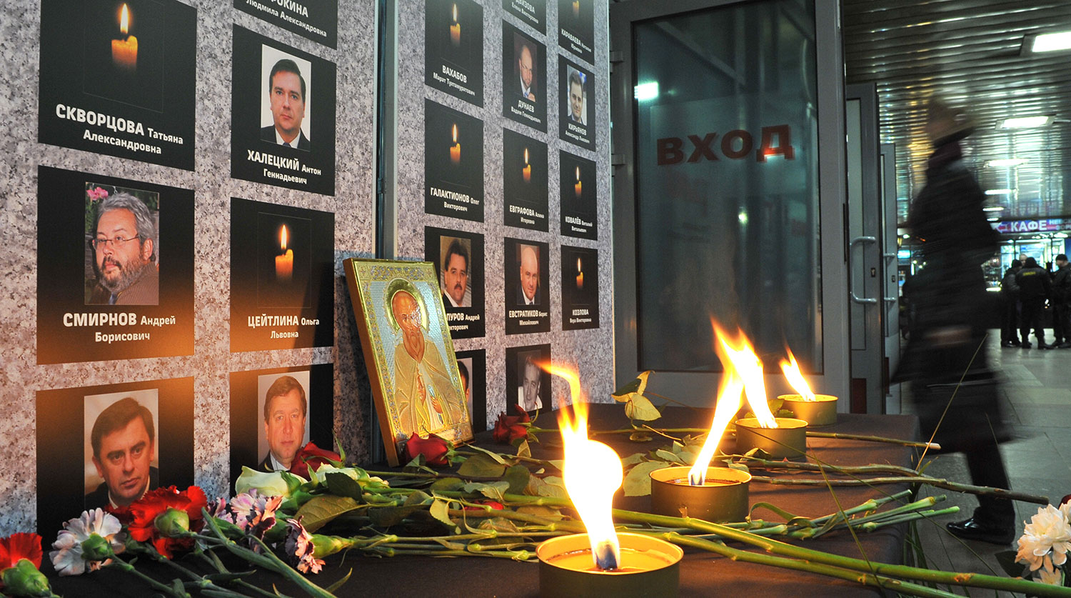 Цветы и свечи у траурной стойки с именами пассажиров, погибших при крушении &laquo;Невского экспресса&raquo; в 2009 году, на Ленинградском вокзале