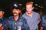 Алан Ширер в сопровождении полиции в аэропорту Сингапура, 1996 год
