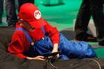 Подросток, одетый в костюм Марио, играет в Nintendo DS во время выставки Gamescom 2010 в Кельне