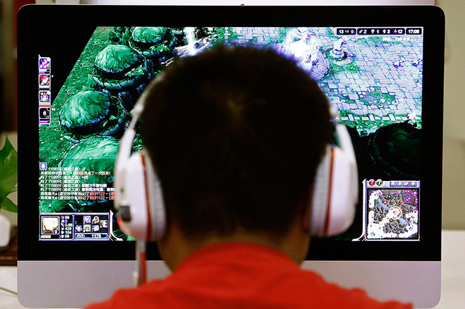 Молодой человек играет в компьютерную игру в пекинском интернет-кафе
