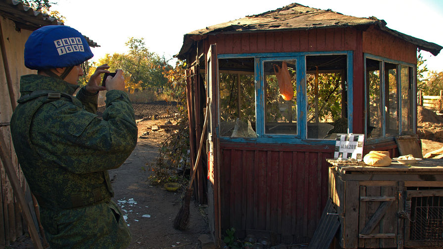 Сотрудник Совместного центра контроля и координации режима прекращения огня во время изучения последствия обстрела поселка Марьевка в Луганской области, 14 октября 2018 года