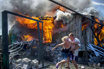 Местные жители спасаются от пожара в доме, пострадавшем во время авиационного удара вооруженных сил Украины по станице Луганская