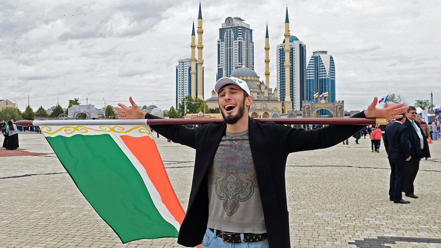 Мужчина с флагом Чеченской Республики на площади имени Ахмата Кадырова