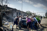 Местные жители отгоняют автомобиль от горящего дома в станице Луганская, подвергшейся авиационному удару вооруженных сил Украины