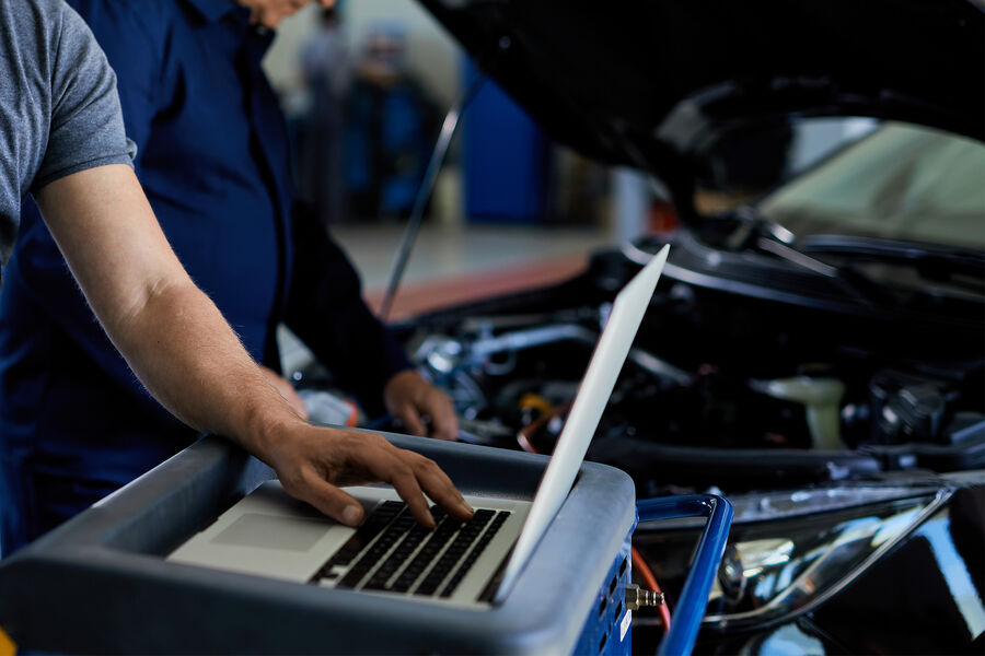 mid-adult-mechanic-working-laptop-while-running-car-diagnostic-with-his-coworker-auto-repair-shop-pic_32ratio_900x600-900x600-90999.jpg