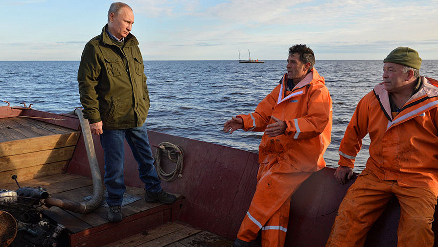 Президент РФ Владимир Путин (слева) во время посещения рыболовецкой лодки на озере Ильмень