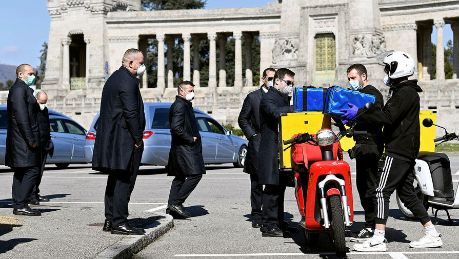 Водители катафалков во время получения заказанной пиццы около кладбища в Бергамо, 16 марта 2020 года