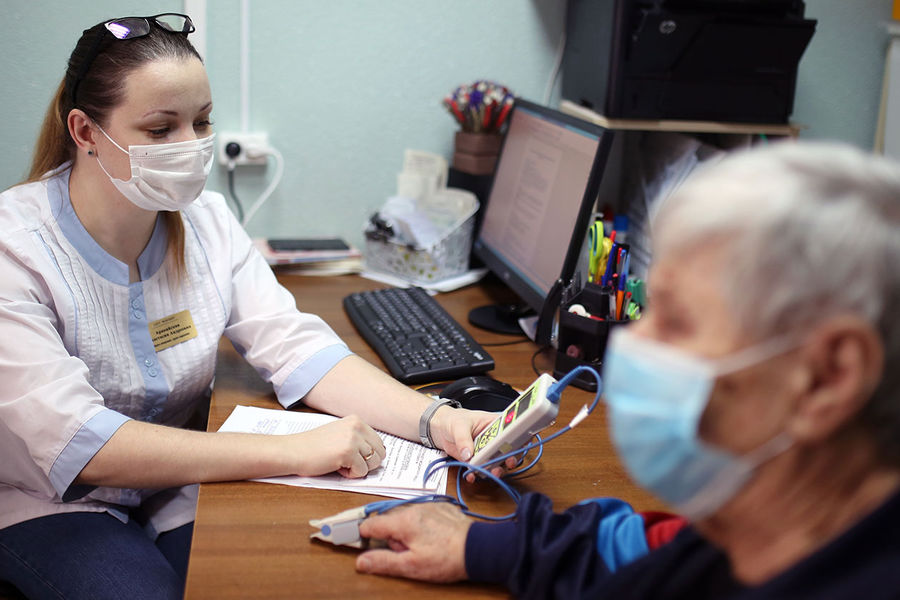 Врач измеряет концентрацию кислорода в крови у пациента, перенесшего коронавирус, в Волгоградском областном клиническом центре медицинской реабилитации