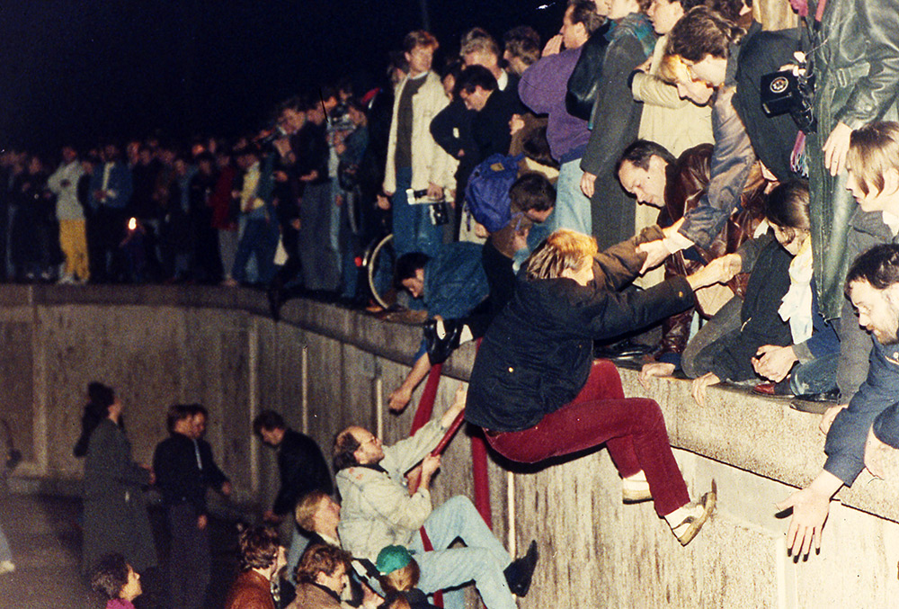 Люди поднимаются на Берлинскую стену 10 ноября 1989 года возле Бранденбургских ворот