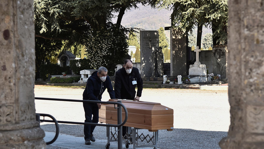 Люди в защитных масках во время транспортировки гроба на кладбище в Бергамо, 16 марта 2020 года