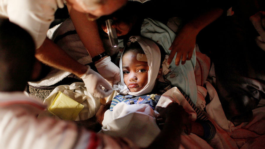 Пострадавшему в результате землетрясения ребенку оказывают помощь, Гаити, 2010 год