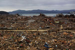 Выживший житель города Минамисанрику спустя несколько дней после цунами едет среди развалин домов 