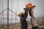Рабочие несут кирпичи в Гувахати, Индия, 21 февраля 2023 года