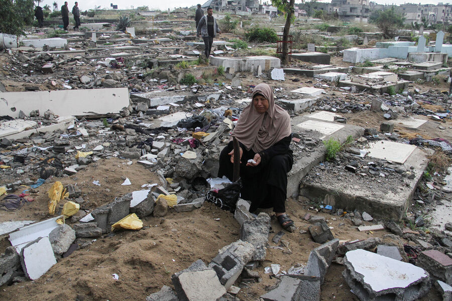 Женщина сидит у могилы в секторе Газа, 10 апреля 2024 года 