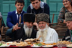 Старейшины за столом во время выступления фольклорной группы на праздновании Дня города в Грозном
