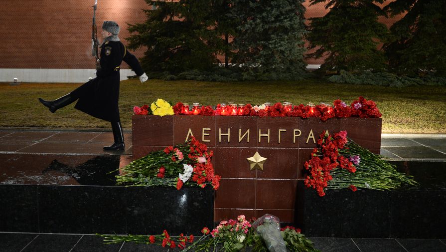 Люди приносят цветы и свечи на мемориал города Ленинграда на аллее городов-героев в Москве
