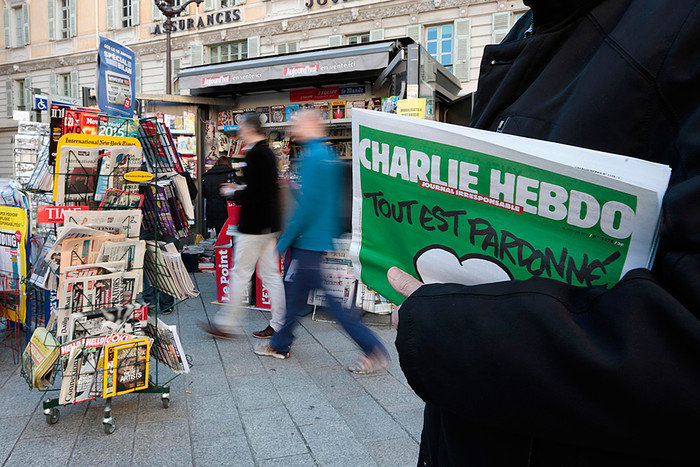 Мужчина держит новый выпуск сатирического французского еженедельника Charlie Hebdo
