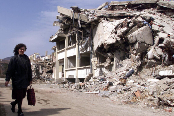 Женщина проходит мимо разбомбленного здания на севере сербской провинции Косово, 2000 год 