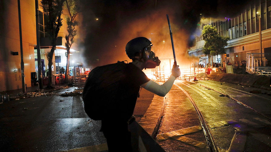 Демонстрант на фоне горящей баррикады во время акции протеста в Гонконге, 31 августа 2019 года