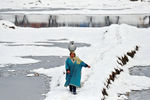 Женщина с кувшином воды идет по заснеженному полю на окраине Сринагара, 9 января 2022 года