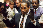 О.Джей Симпсон примеряет перчатки перед присяжными во время суда, найденные полицией Лос-Анджелеса и использованные в качестве доказательства по делу об убийстве Николь Браун-Симпсон и Роналда Голдмана, 1995 год