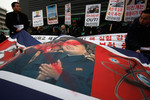Перечеркнутый портрет северокорейского лидера в руках демонстрантов, собравшихся у здания американского посольства в Сеуле после того, как Пхеньян объявил об испытании ядерного оружия. Митингующие на втором плане держат плакаты с надписью «Безумных собак нужно бить».
