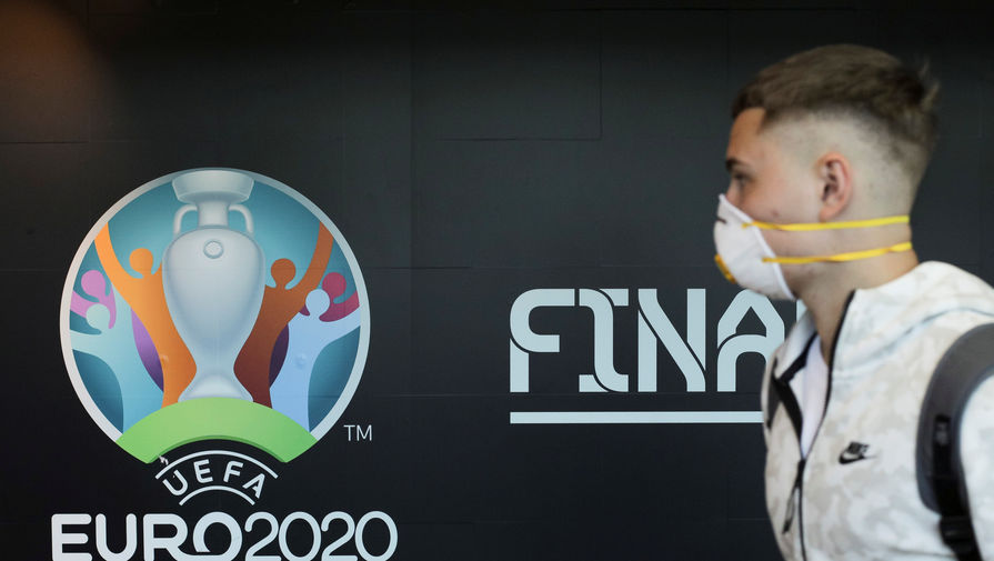 Человек в маске от коронавируса на фоне логотипа Евро-2020 по футболу