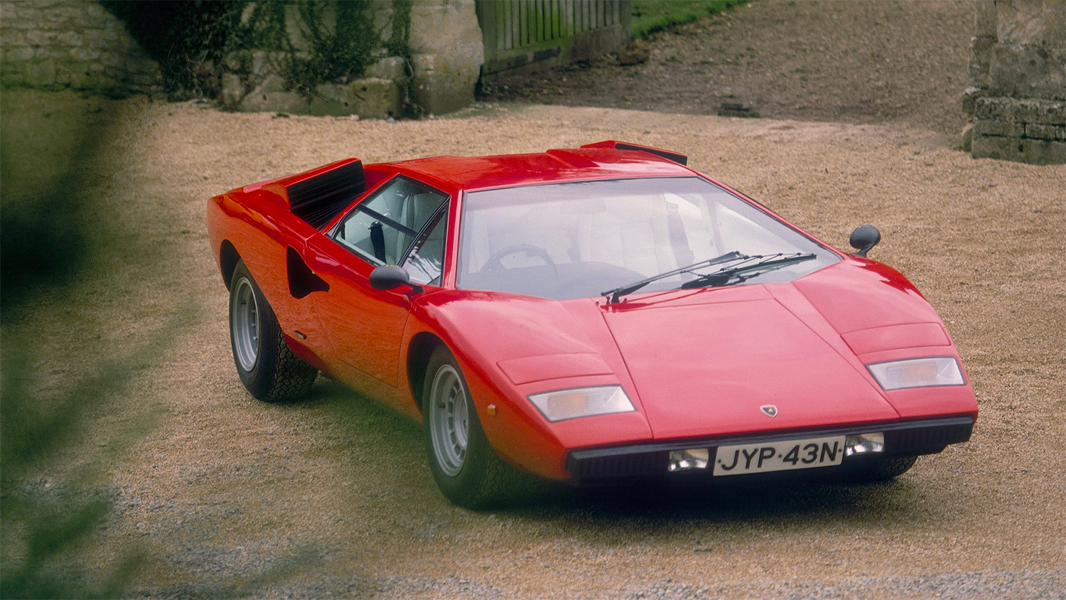<b>Lamborghini Countach</b> (годы выпуска: 1974&nbsp;- 1990). Дизайн автомобиля разрабатывал&nbsp;Марчелло Гандини, он же ранее разрабатывал дизайн&nbsp;Miura и Jarama. В те годы Гандини был молодым и не очень опытным дизайнером, он мало ориентировался в&nbsp;эргономике&nbsp;автомобиля и оригинальный дизайн Countach&nbsp;&mdash; это его представление автомобиля, практически не искажённое правилами и традициями автомобилестроения. Countach получился угловатым, широким и низким. Фактически корпус состоял из множества трапециевидных плоскостей. Хотя в автомобиле и присутствовали плавные линии, они не смягчали внешней угловатости.<br>
Двери автомобиля, своеобразная визитная карточка Countach, а впоследствии и других моделей Ламборгини, были&nbsp;гильотинного типа&nbsp;(«двери-ножницы»)&nbsp;&mdash; для открытия дверь поднималась и отталкивалась вперёд. Хотя это и оказалось интересным дизайнерским решением, в первую очередь это было сделано из-за большой ширины автомобиля: стандартные двери в данном случае были бы весьма неудобны.