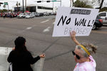 Люди, выступающие против воздвижения стены на границе США и Мексике, ожидают приезд президента США Дональда Трампа в Мак-Аллен