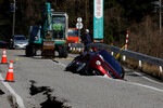Машина застряла в трещине на дороге после землетрясения, недалеко от Удзимы, 2 января 2024 года 