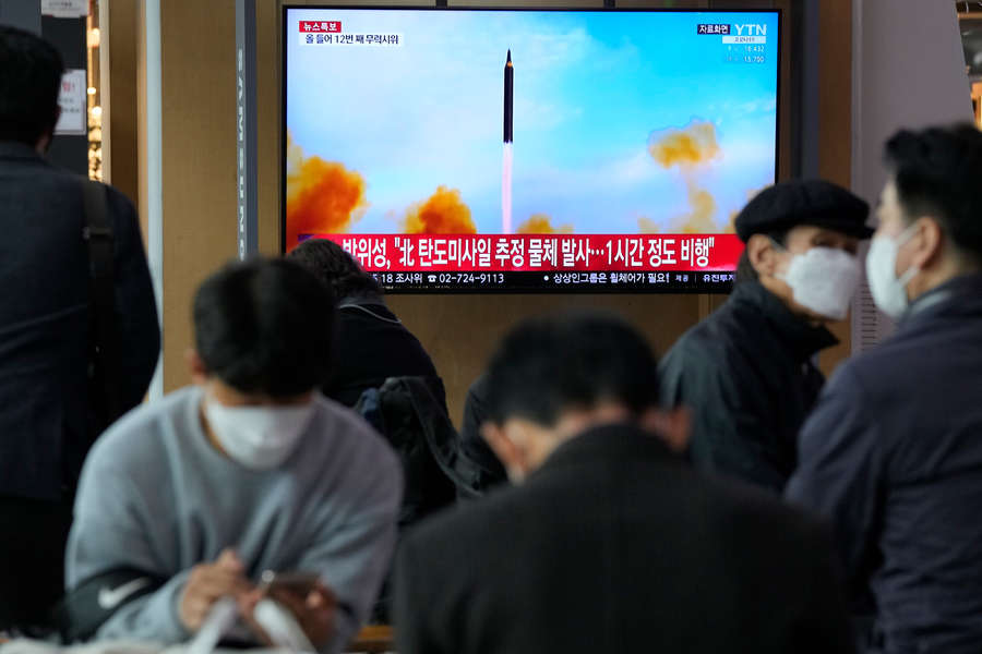 Люди смотрят телевизор, показывающий изображение запуска северокорейской ракеты во время программы новостей на железнодорожном вокзале в Сеуле, Южная Корея, 24 марта 2022 года
