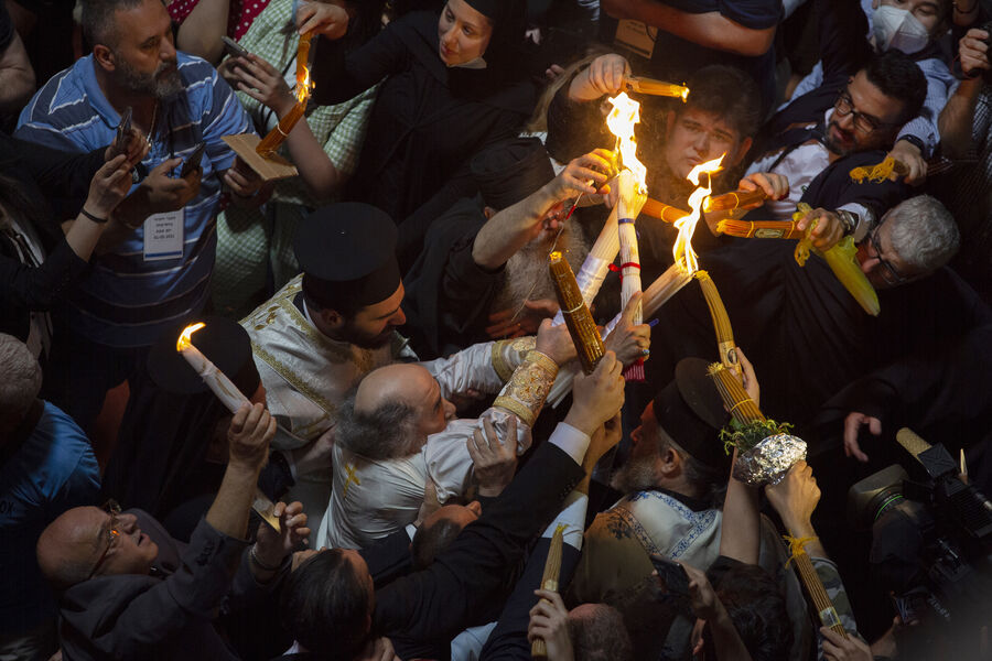 Греческий православный патриарх Иерусалима Феофил III (слева) держит свечи для христианских паломников во время церемонии зажжения Благодатного огня в храме Гроба Господня, Иерусалим, 2021 год