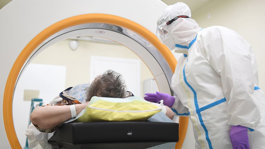 Врач помещает пациентку в аппарат компьютерной томографии во временном госпитале для больных COVID-19
