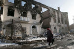 Женщина проходит мимо разрушенного здания в городе Углегорск под Донецком