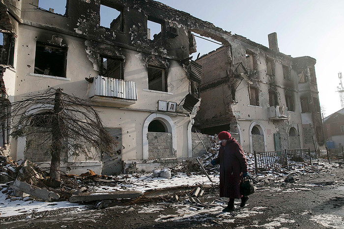 Женщина проходит мимо разрушенного здания в&nbsp;городе Углегорск под&nbsp;Донецком