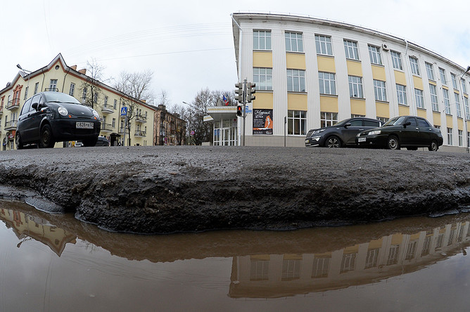 Глубокая яма, заполненная водой, на разбитом дорожном покрытии Большой Московской улицы в Великом Новгороде