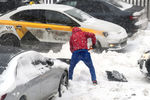 Мужчина откапывает из сугроба свою машину во дворе жилого дома в Москве, 13 февраля 2021 года