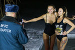 Сотрудник МЧС Белоруссии фотографирует девушек во время крещенских купаний в купели в Цнянском водохранилище, 18 января 2019 года