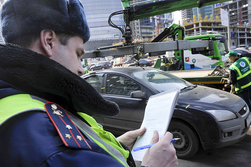 Сотрудник ДПС заполняет протокол во время эвакуации автомобиля с парковки в неположенном месте